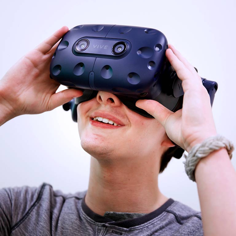 A student looks into a set of virtual reality goggles. 